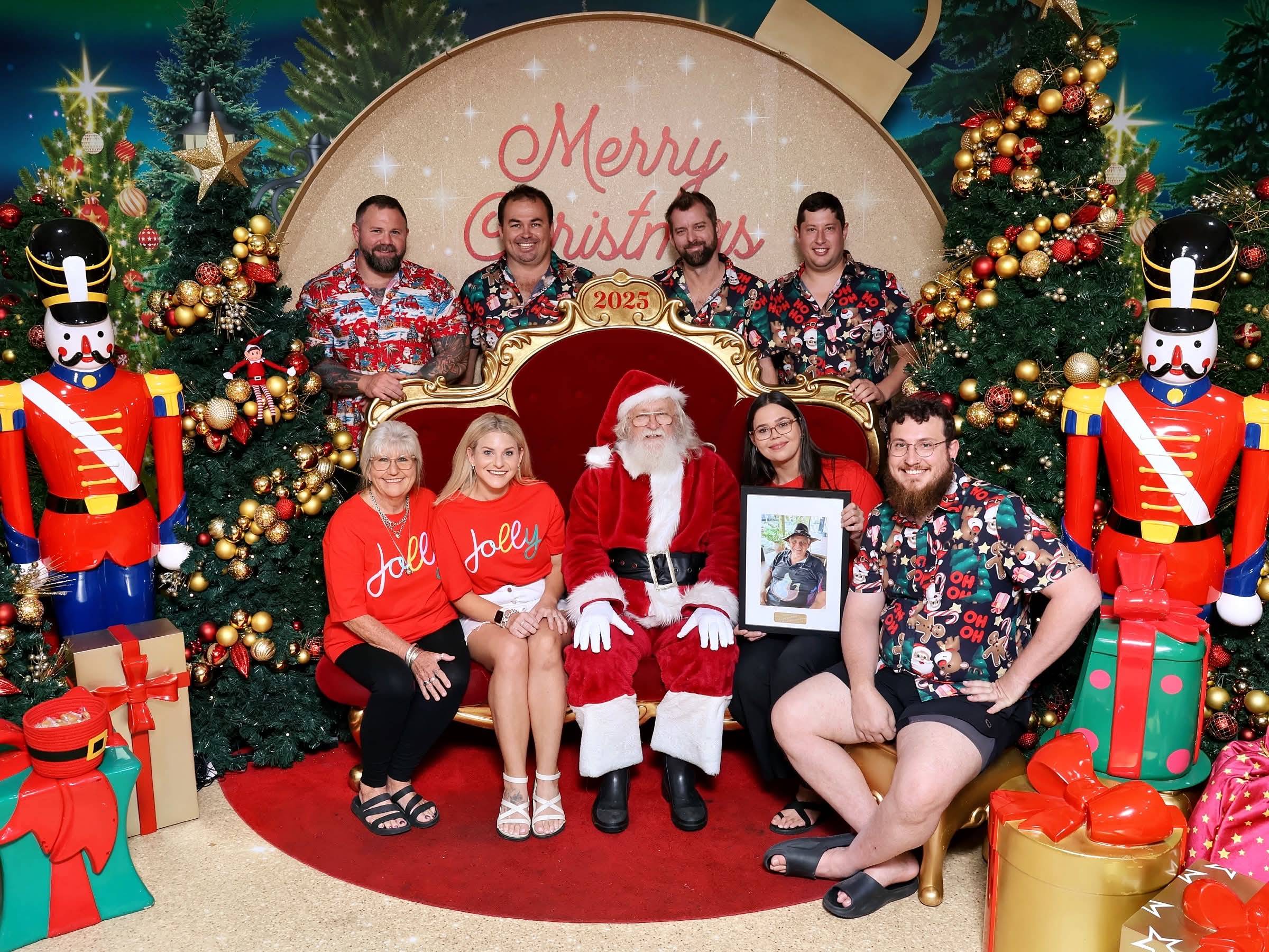 Advanced Smoke Alarms team and family at Christmas 2025, holding a portrait of co-founder Wayne Gregory